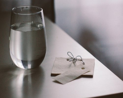 A glass of water next to a notebook on a wooden table